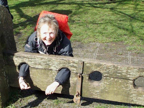 53.Holiday 2016  - The Peak District
7/4/16. Cath tries out the stocks on the village green at Eyam. Photo: Dafydd Williams.
Keywords: Apr16 Week Ian Spencer