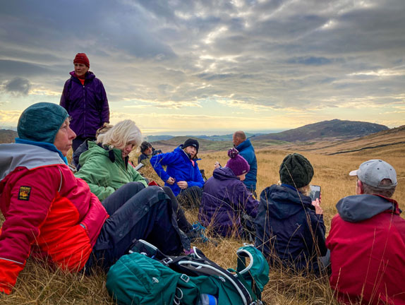 3.Cwm Pennant: Cae Amos - Cwm Ciprwth
4/12/22. The morning coffee/tea break. Just about out of the chilly breeze. Graig y Garn  and Tremadog Bay in the background. Photo: Annie Andrew.
Keywords: Dec22 Sunday Eryl Thomas