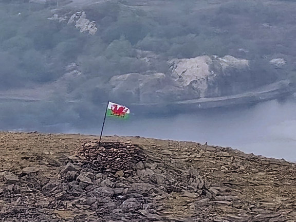 7. Pedol Marchlyn Horseshoe
26/04/26. On our way down from Elidir Fawr, the cairn sporting the Welsh Dragon flag. marking the summit of Elidir Fach . Photo: Mags McQuillan Jones
Keywords: Apr26 Sunday Gareth Hughes