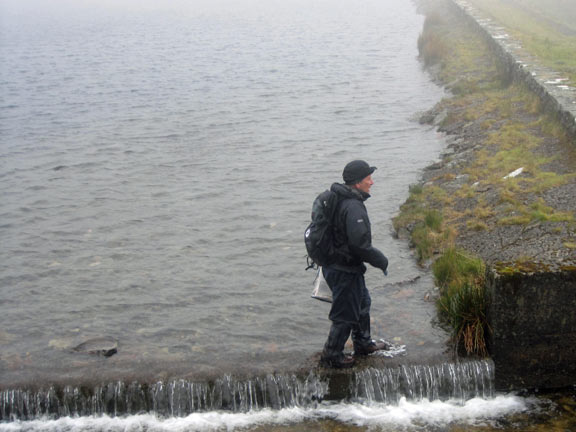 The spillway at Llyn Llygad Rheidol as a member makes his way across.