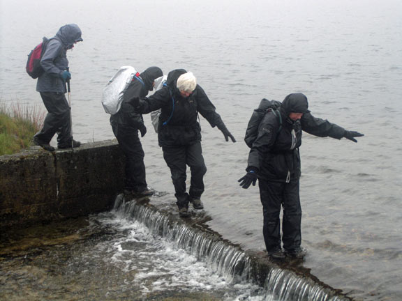 The spillway at Llyn Llygad Rheidol as members make their way across.