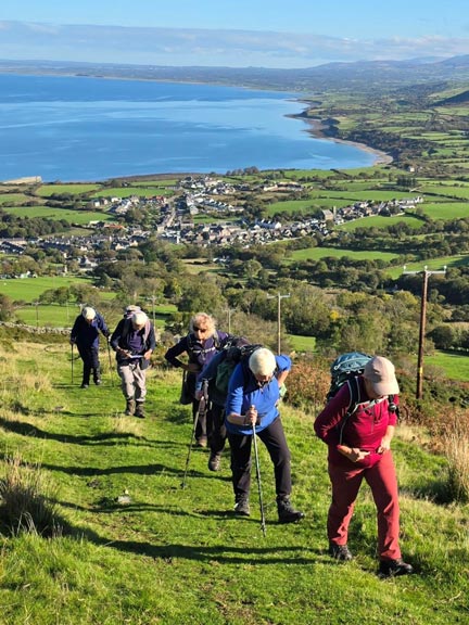 3. Three Peaks of Yr Eifl
18/10/26. The long slog up Nant-y-Cwm to Bwlch yr Eifl where we will stop for a panad (cuppa). The village of Trefor can be seen in the background and beyond it Caernarfon Bay. Photo: Mags McQuilling Jones.
Keywords: Oct26 Sunday Gareth Hughes
